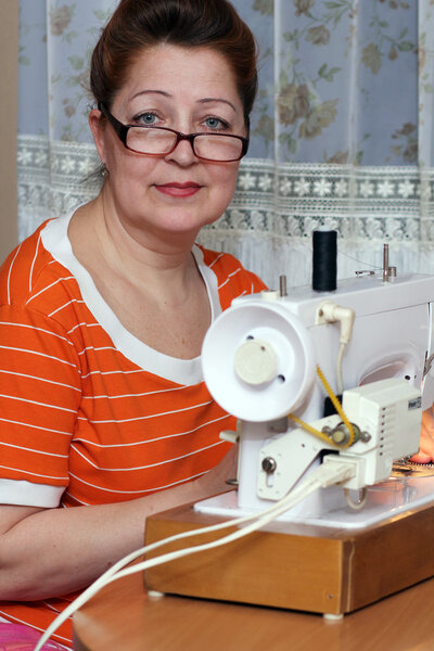 Old woman sews clothes in-home