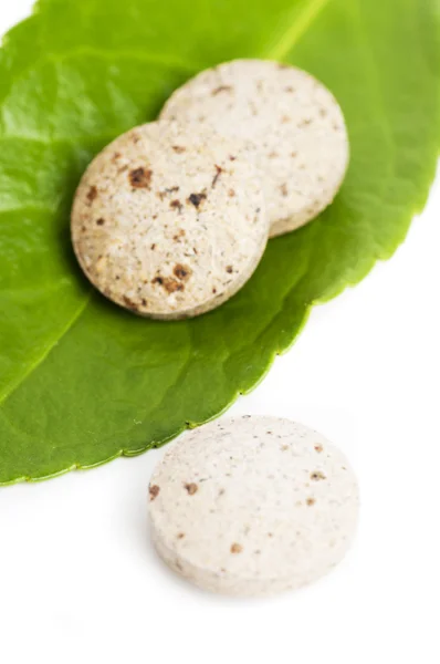 Naturalne tabletki na zielony liść na białym tle — Zdjęcie stockowe