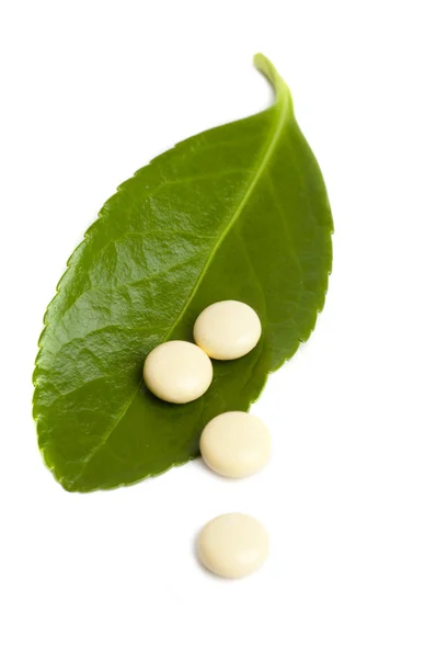 Natuurlijke pillen over groene blad geïsoleerd — Stockfoto