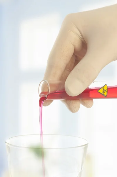 Mão Segurando um tubo de teste com símbolo de risco biológico — Fotografia de Stock