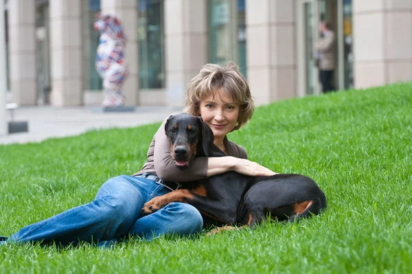 年轻的女人与一条狗在草地上 — 图库照片