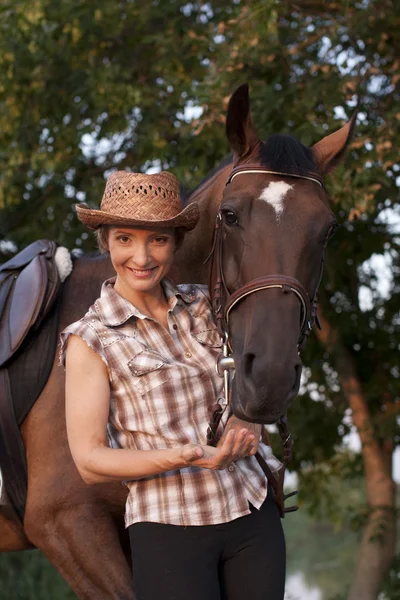 Joven mujer sostener caballos cabeza — Foto de Stock
