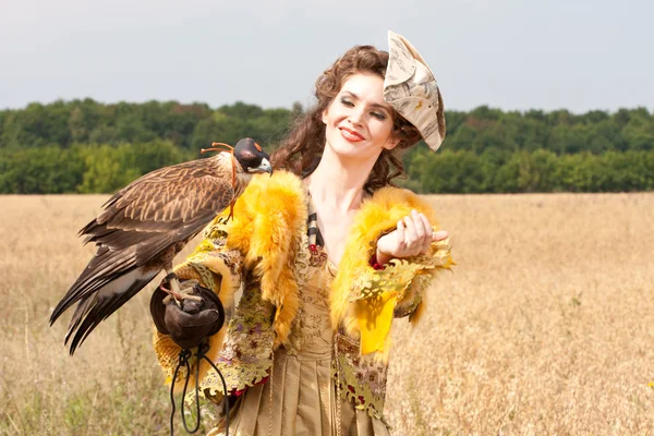 Kvinnan i en vacker gammal stil klänning med falcon har en vila — Stockfoto