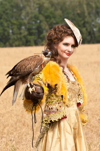 The woman in a beautiful old style dress with falcon has a rest — Stock Photo, Image