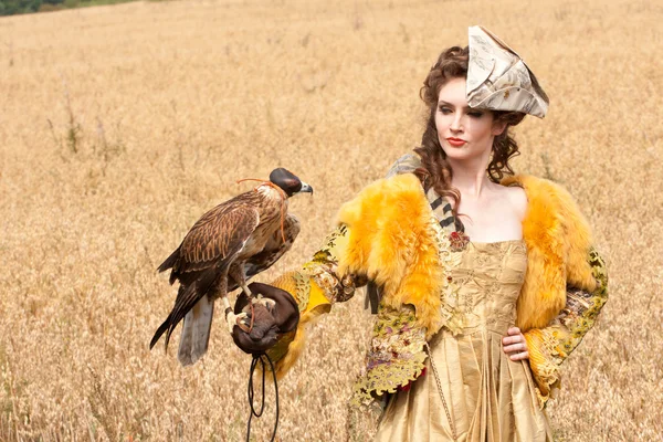 La femme dans une belle robe de style ancien avec le faucon a un repos — Photo