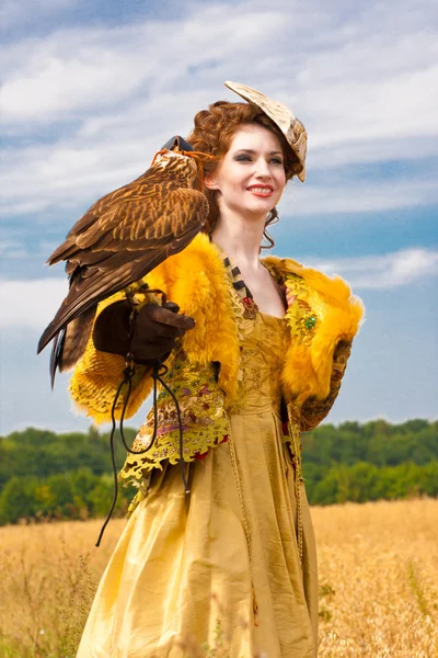 La femme dans une belle robe de style ancien avec le faucon a un repos — Photo