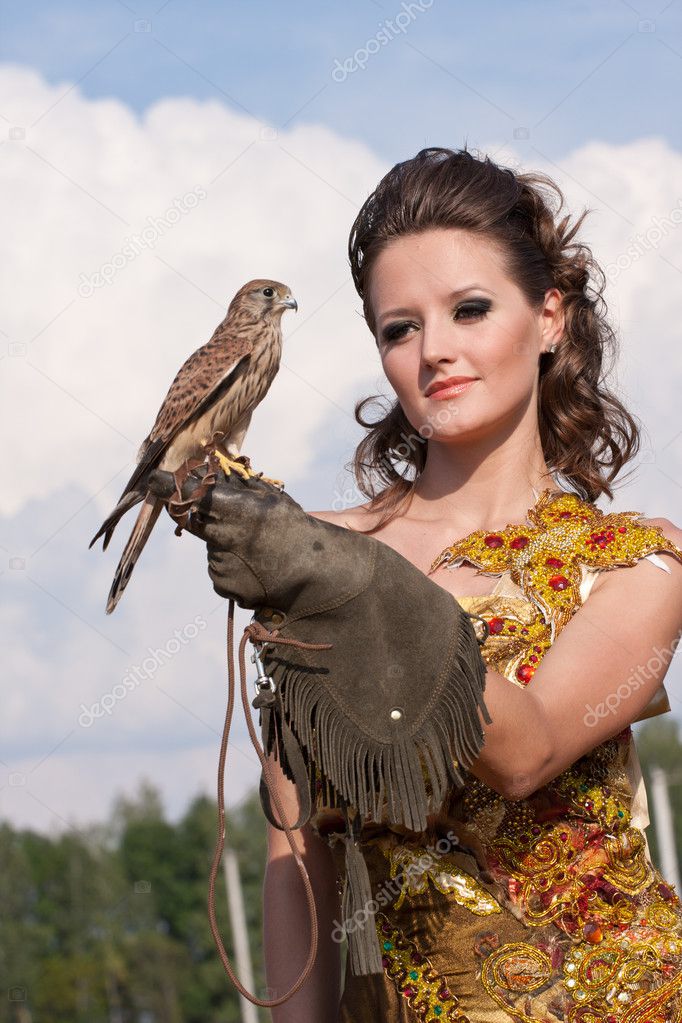 The woman in a beautiful old style dress with falcon