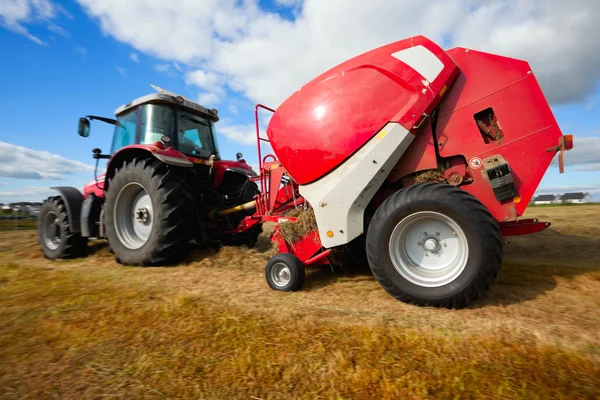 Трактор собирает стог сена в поле, технику панорамирования — стоковое фото