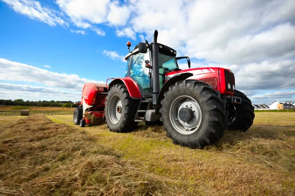 Traktor sammelt Heuhaufen auf dem Feld — Stockfoto