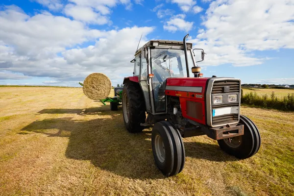 Tractor recogiendo un rollo de pajar en el campo —  Fotos de Stock
