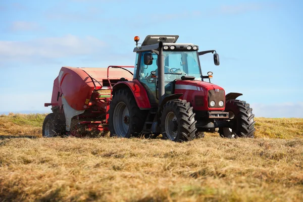 Трактор собирает стог сена в поле — стоковое фото
