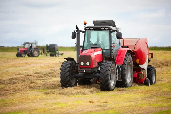 Två traktorer samla höstack i fältet — Stockfoto