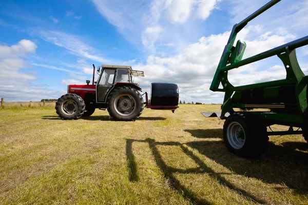 Traktor sammelt Heuhaufen im Feld ein — Stockfoto