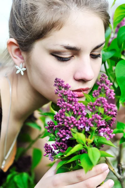 Adolescente menina cheirando flores lilás — Fotografia de Stock