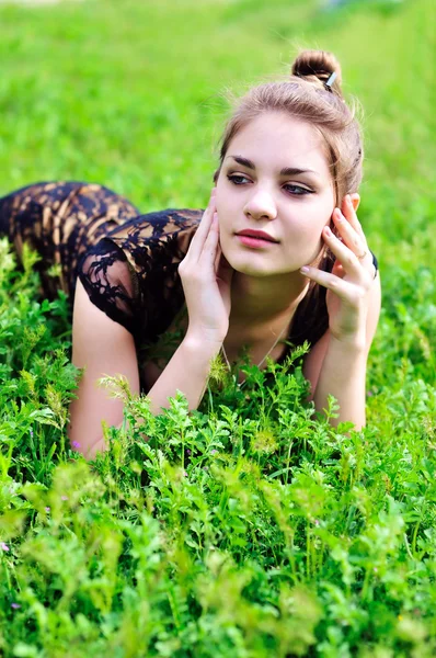 Menina que estabelece em grama verde brilhante — Fotografia de Stock