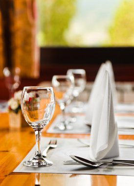 Glasses and plates on table in restaurant clipart