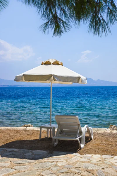 Стул и зонтик на греческом пляже — стоковое фото