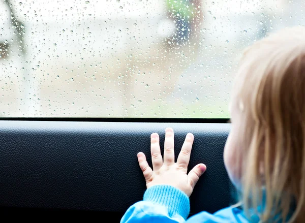 Flicka i en bil ser ut genom fönstret — Stockfoto