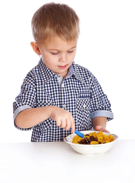 Um menino está comendo cereais de uma tigela — Fotografia de Stock