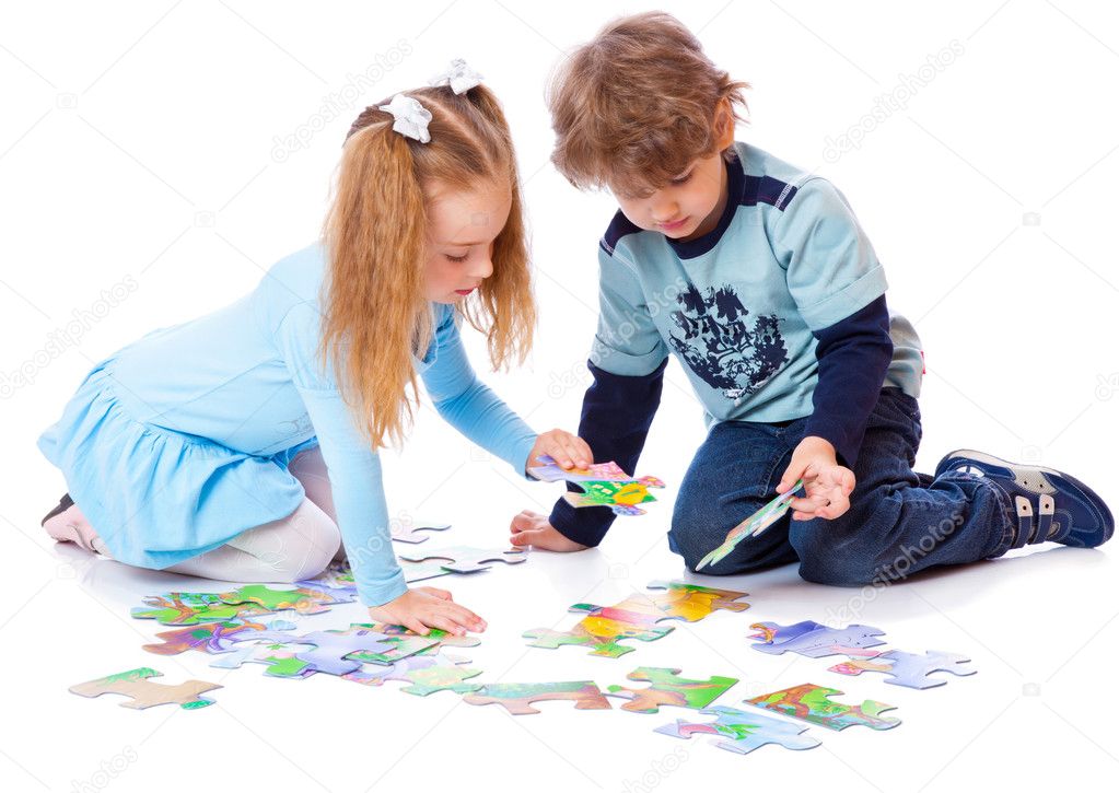 Boy and girl are playing with puzzle