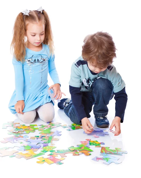 Boy and girl are playing with puzzle — Stock Photo, Image