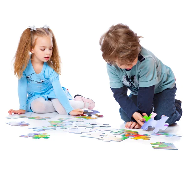 Menino e menina estão jogando com quebra-cabeça — Fotografia de Stock