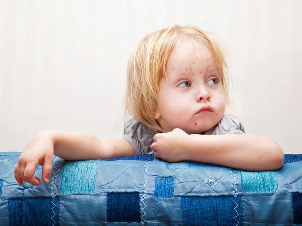 Uma menina doente está sentada perto da cama — Fotografia de Stock