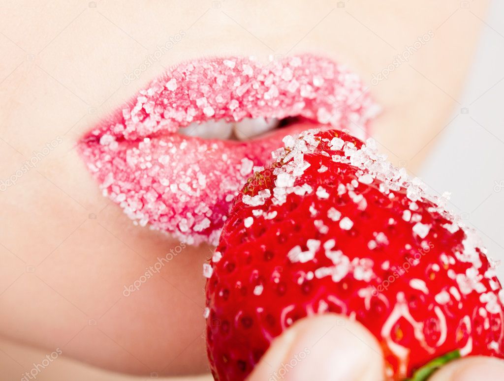 Woman's mouth with red strawberry covered with sugar