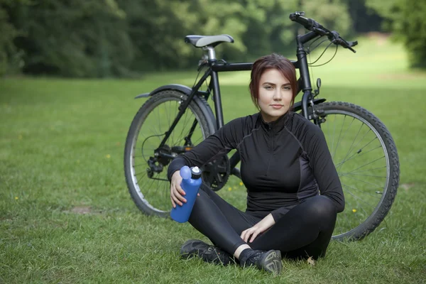 Woman with bike resting on ground — Stockfoto