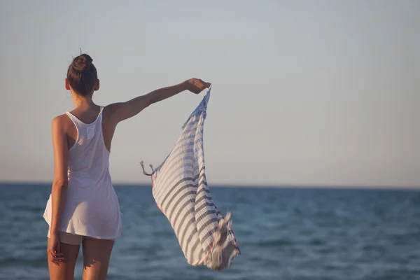 Kvinna anläggning halsduk på stranden — Stockfoto