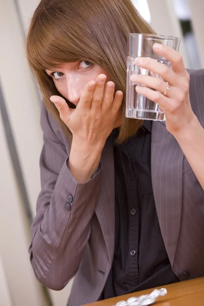 Vrouw nemen pillen door werk — Stockfoto