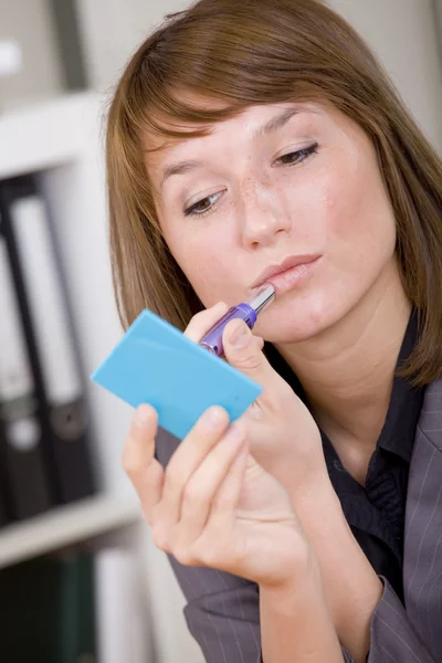 Woman putting on makeup by office work — Stock Photo, Image