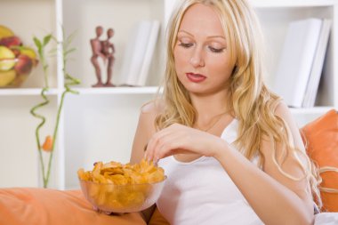 Sad woman eating snacks at home clipart