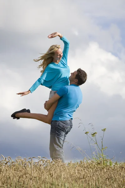 Hombre levantando mujer en el campo — Foto de Stock