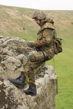 Soldier climbing down the rock clipart