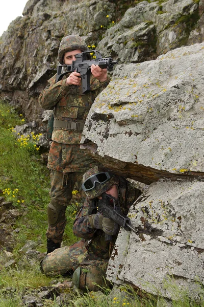 Zwei Soldaten, die sich hinter dem Felsen verschanzen — Stockfoto