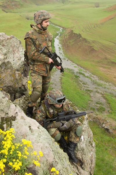 Soldiers in heavy ammunition on the rock — Stock Photo, Image