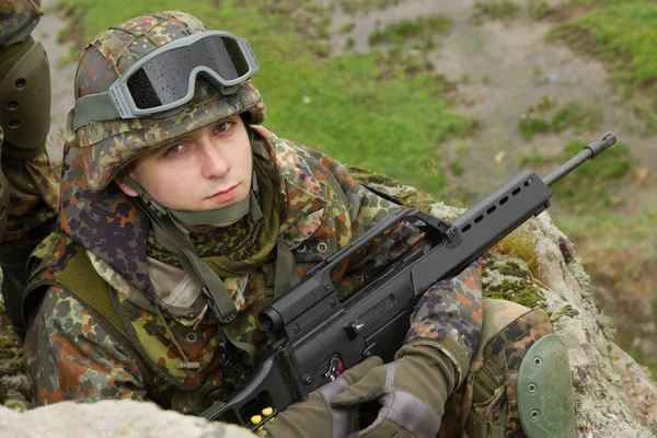 Retrato del joven soldado sentado con un rifle — Foto de Stock