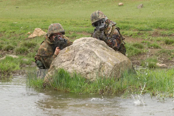 Солдаты, укрывающиеся за скалой — стоковое фото