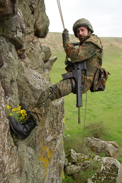 Bevæbnet militær alpinist hængende på reb - Stock-foto