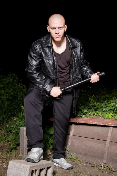 Gângster careca armado com bastão ao ar livre à noite — Fotografia de Stock