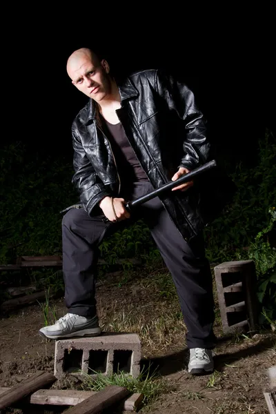 Bald thug armed with baton outdoors at night — Stock Photo, Image