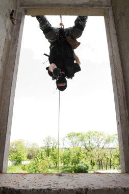 Soldier in black mask hanging on rope with pistol clipart