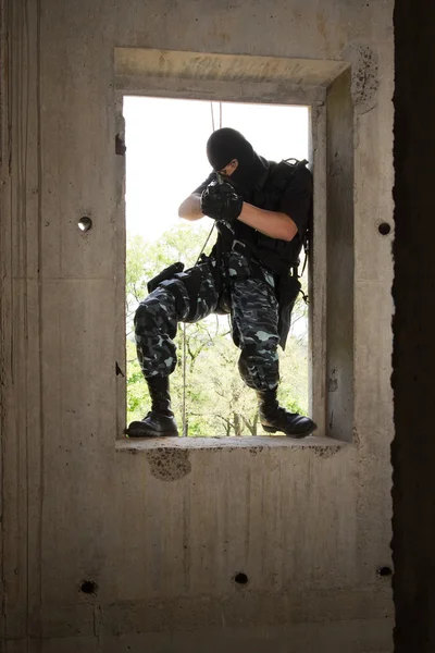 Soldado em máscara preta entrando pela janela — Fotografia de Stock