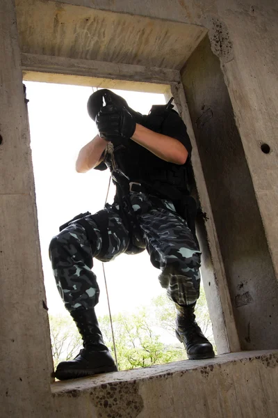 Soldier in black mask entering through the window — Stock Photo, Image