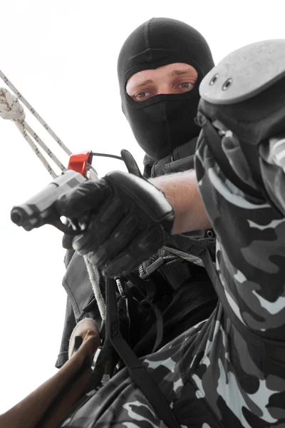 Soldado em máscara preta pendurado na corda com pistola — Fotografia de Stock