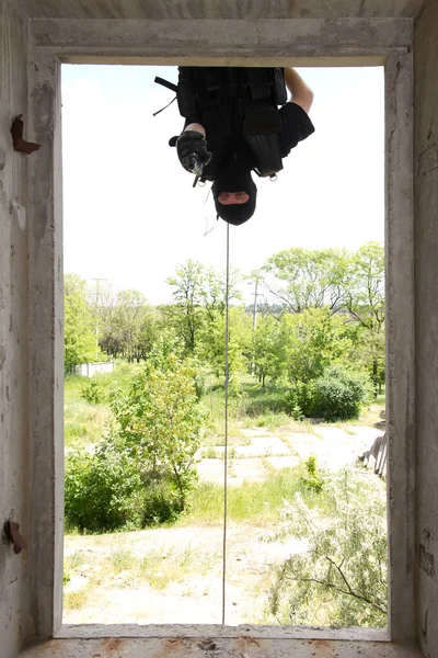 ピストルでロープにぶら下がっている黒いマスクの兵士 — ストック写真