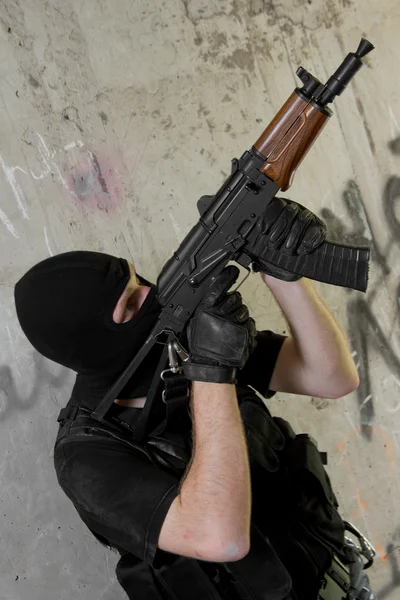 Soldier in black mask moving upstairs with AK-47 rifle — Stock Photo, Image