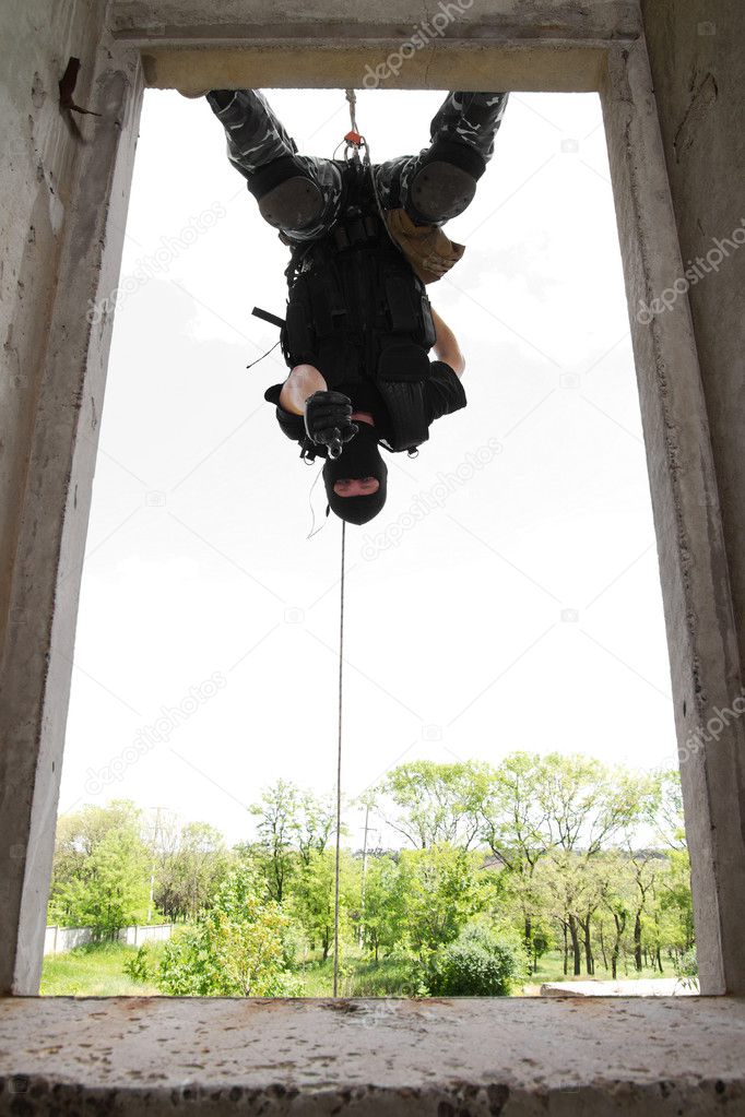 Soldier in black mask hanging on rope with pistol