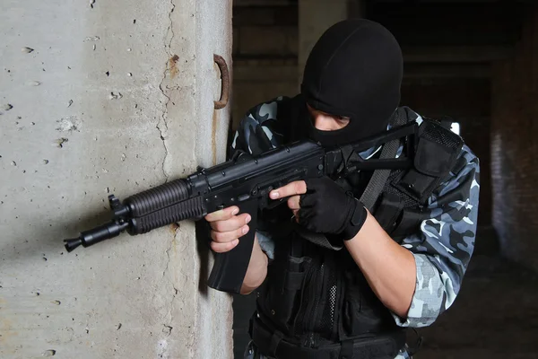 Вооруженный солдат в черной маске целится из пистолета — стоковое фото